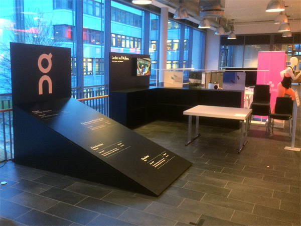 kleiner Messestand mit Regalen, Prsentern und schrgem Podest