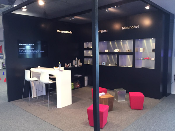 Messestand mit Einbauregalen, Brckentisch, Loungehocker, Beleuchtung
gefrsten Logos und eingebautem Display