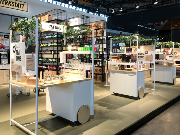 Messestand Kaffeewerkstatt, Stahlregale, Werkstattwagen, Klicklinoleum, geflieste Theke, Durchreiche, verputzte Kabine, Fenster, Anlehnhocker, Beistelltische