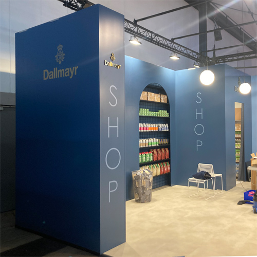 Messestand Shop mit Empfangstheke Streifen, beleuchtetem Shopregal, Hockern, Tischen, Regalen